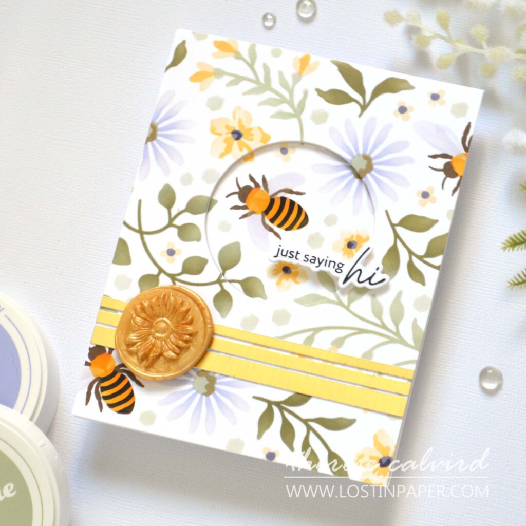 Focal point card with floral stencil background, recessed circular window with bee and sentiment, accented with a small floral wax seal