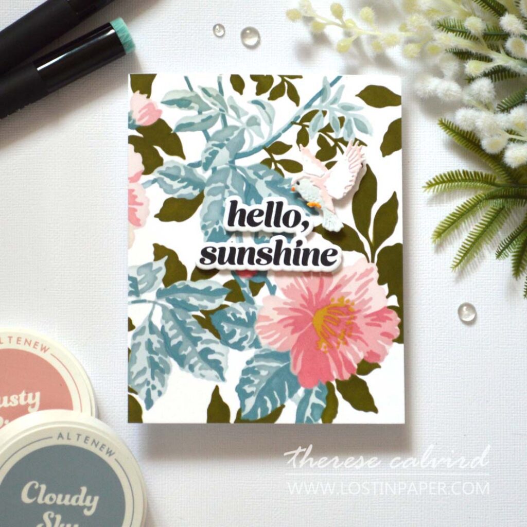 Layered bird die card coloured with alcohol markers on a soft ink blended leafy background with a central popped up stamped sentiment by Therese Calvird