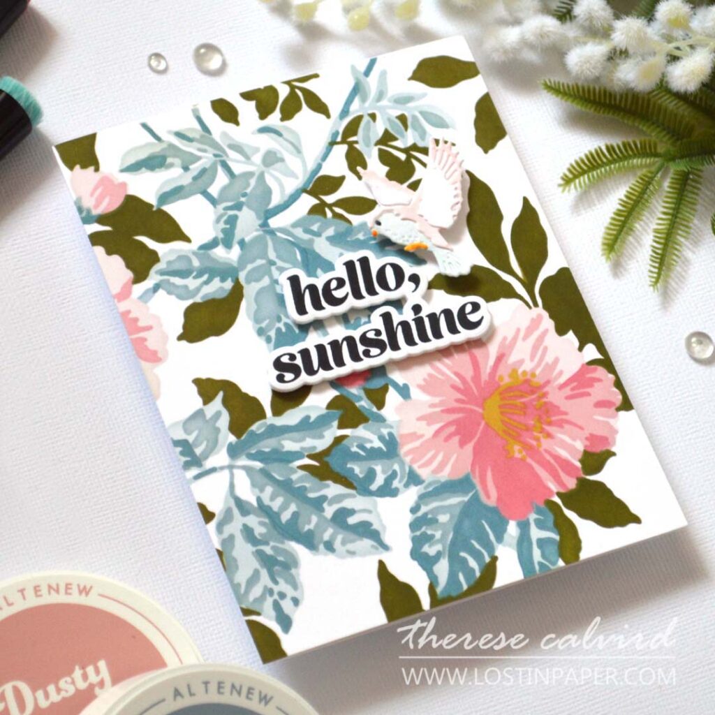 Layered bird die card coloured with alcohol markers on a soft ink blended leafy background with a central popped up stamped sentiment by Therese Calvird