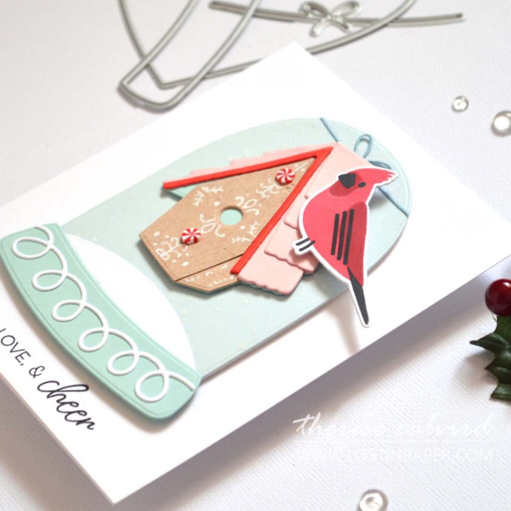 Clean and simple layered stamped bird card featuring a gingerbread-style birdhouse hung from a snow globe with a cardinal perched on the roof by Therese Calvird