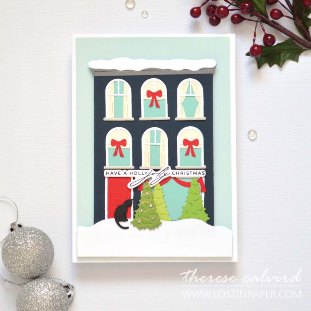 Jolly Christmas house card featuring a die-cut city building with a black cat at the front door by Therese Calvird.