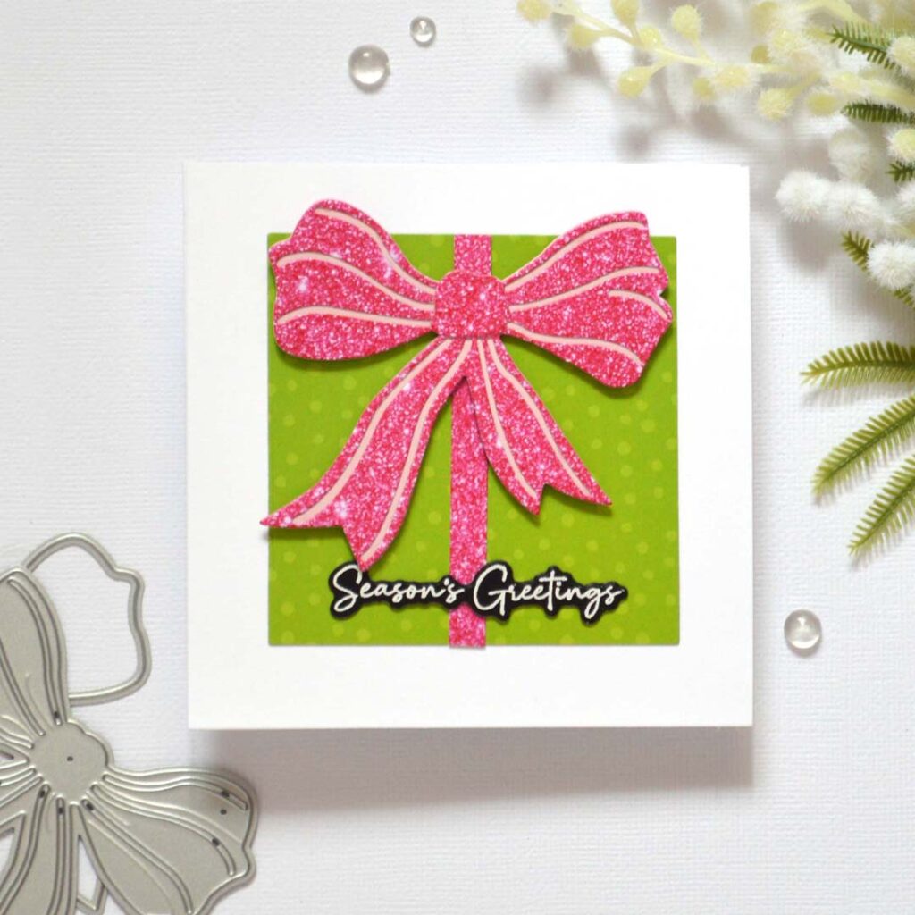 Christmas card from Therese Calvird’s Same But Different Christmas series featuring a die-cut gift box made with patterned paper and a faux glitter bow.