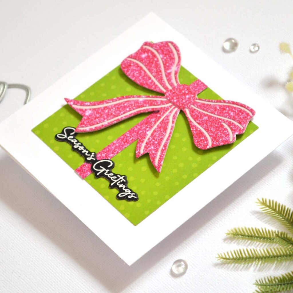 Christmas card from Therese Calvird’s Same But Different Christmas series featuring a die-cut gift box made with patterned paper and a faux glitter bow.