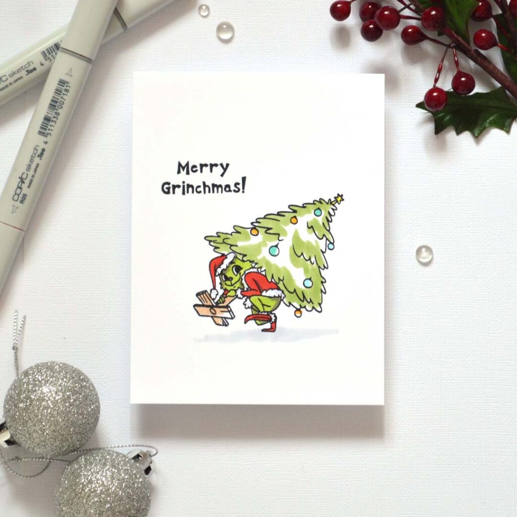 Playful handmade card from Therese Calvird’s Same But Different Christmas series featuring the Grinch running away with a Christmas tree, colored with alcohol markers.