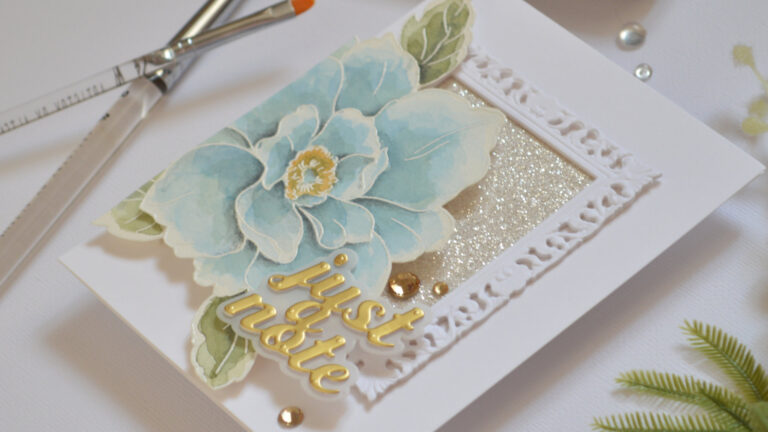 Handmade card featuring an ornate picture frame with glitter paper and a large blue watercolor bloom by Therese Calvird