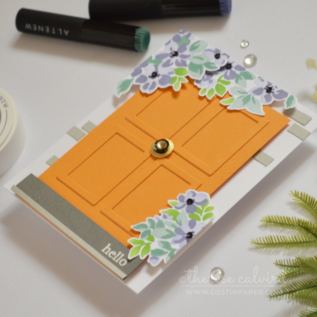 Bright orange door card with small picture frames used as wood panels, decorated with flowers and a rhinestone door knob by Therese Calvird