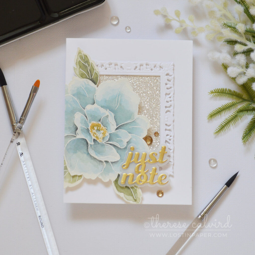Handmade card featuring an ornate picture frame with glitter paper and a large blue watercolor bloom by Therese Calvird