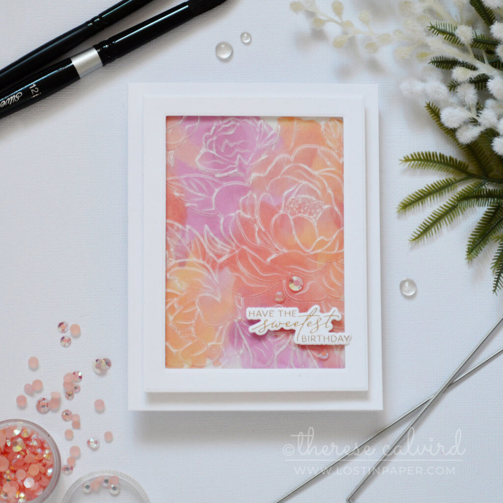 Embossed vellum floral panel over a pink and orange watercolour background with gold foiled sentiment by Therese Calvird