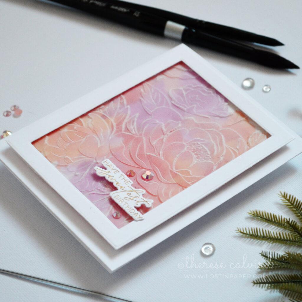 Embossed vellum floral panel over a pink and orange watercolour background with gold foiled sentiment by Therese Calvird