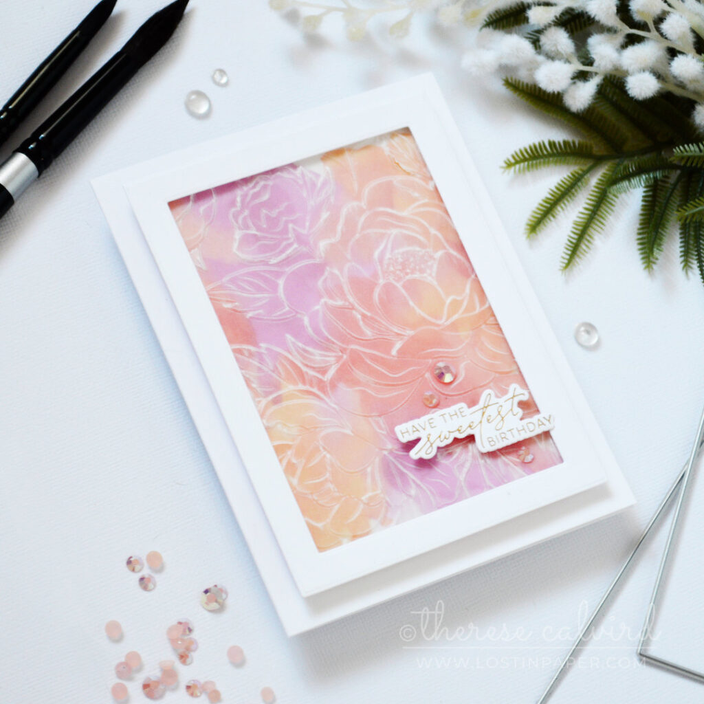 Embossed vellum floral panel over a pink and orange watercolour background with gold foiled sentiment by Therese Calvird