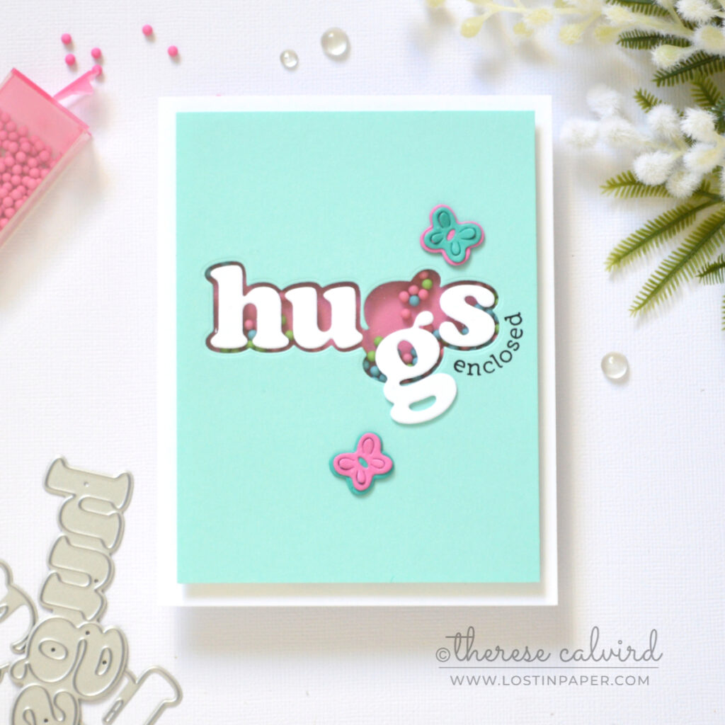 Hugs shaker card with die cut window and bright candy shaker elements by Therese Calvird