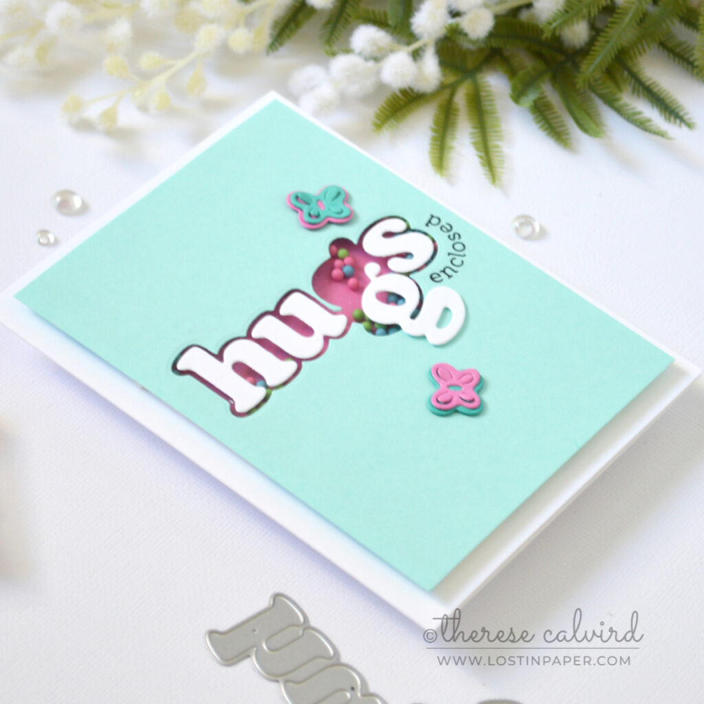 Hugs shaker card with die cut window and bright candy shaker elements by Therese Calvird