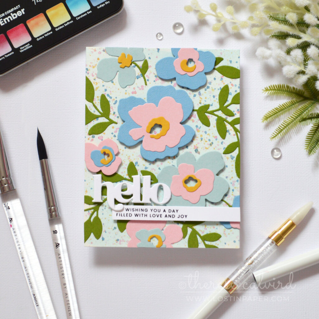 Watercolor wash background with masked floral areas and layered die cut flowers and leaves