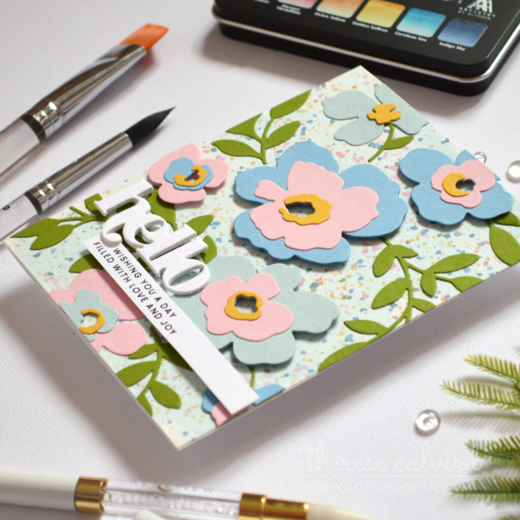 Watercolor wash background with masked floral areas and layered die cut flowers and leaves