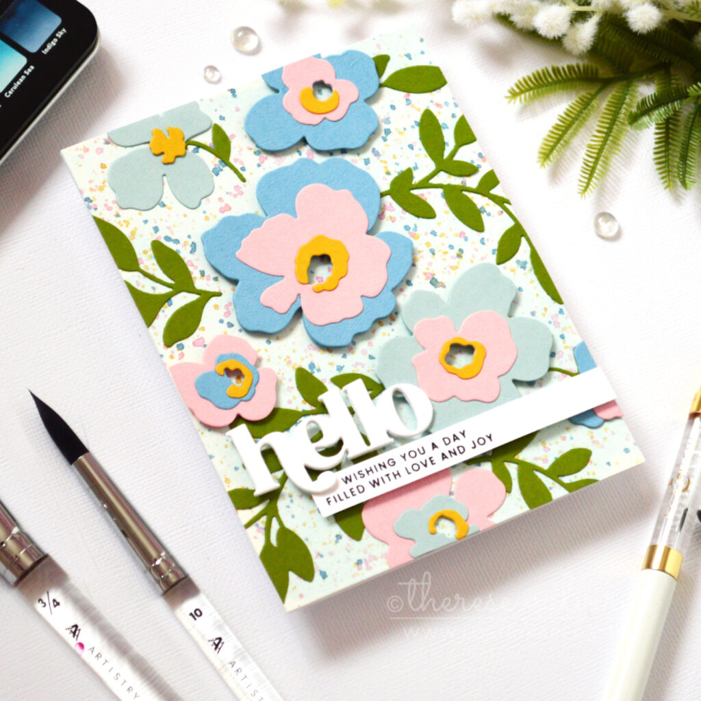 Watercolor wash background with masked floral areas and layered die cut flowers and leaves