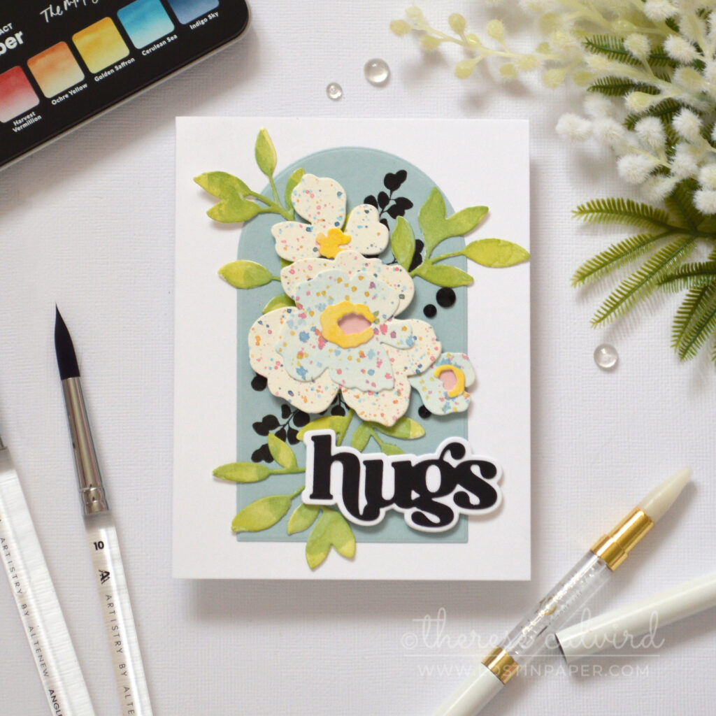 Watercolor splattered floral shapes arranged as a bouquet on an arched panel with a bold die cut sentiment