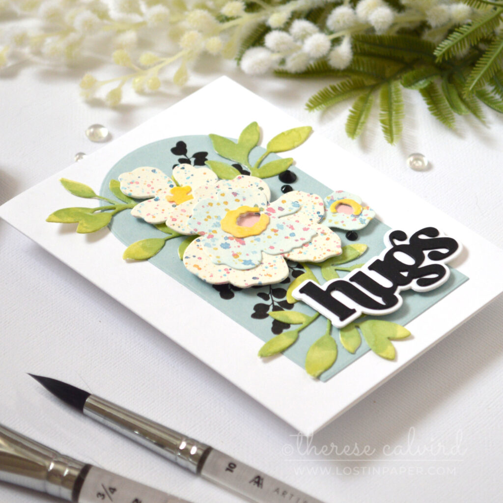 Watercolor splattered floral shapes arranged as a bouquet on an arched panel with a bold die cut sentiment