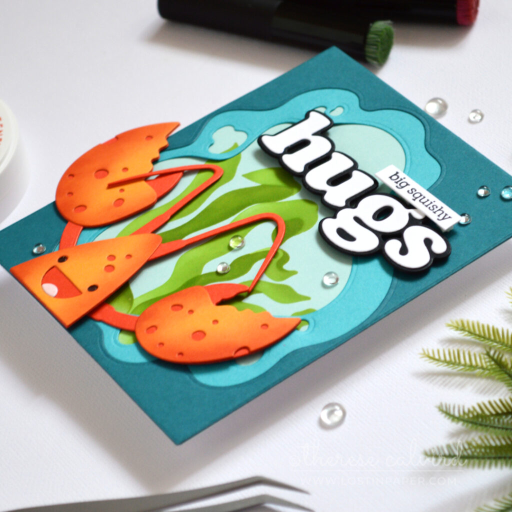 Handmade lobster hugs card with an ocean window frame, seaweed background, and large die cut sentiment.