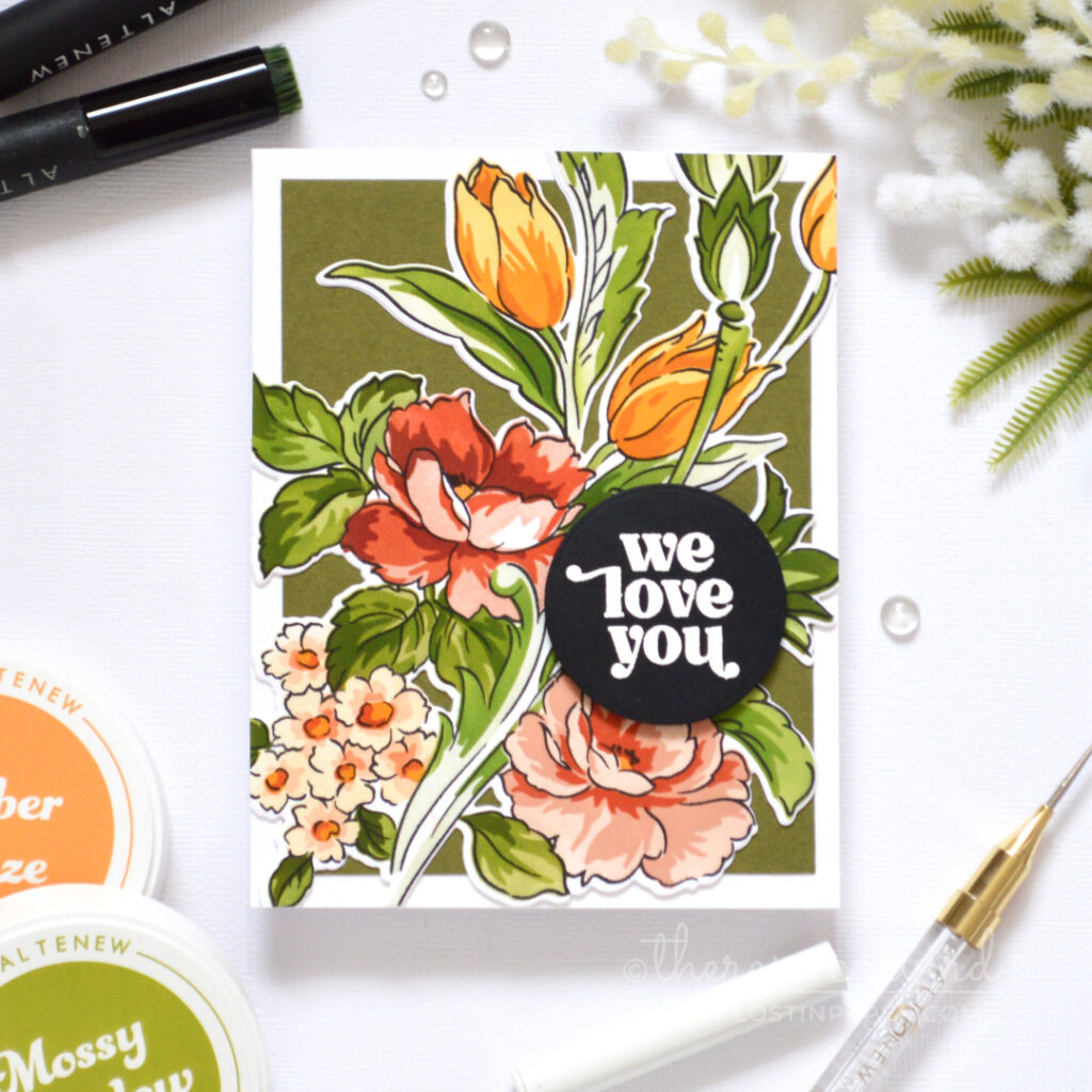Floral card in warm coral, gold and green tones with layered dimension and a white embossed sentiment on a black circle.