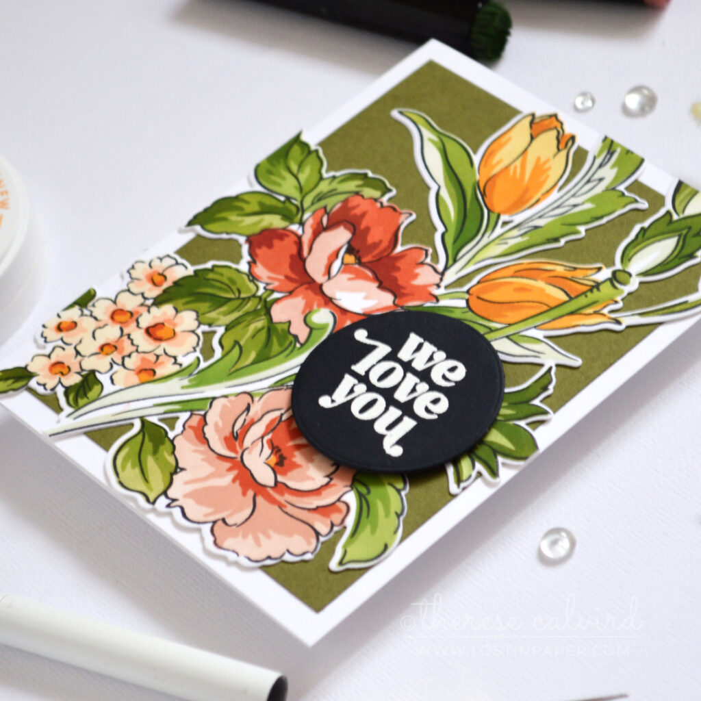 Floral card in warm coral, gold and green tones with layered dimension and a white embossed sentiment on a black circle.