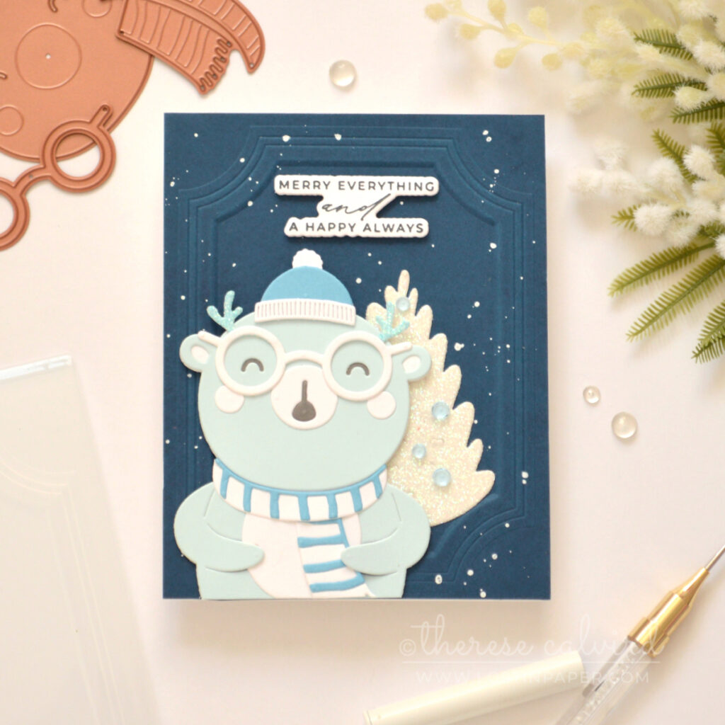 Blue bear Christmas card with a glittery white tree and dark blue embossed background.