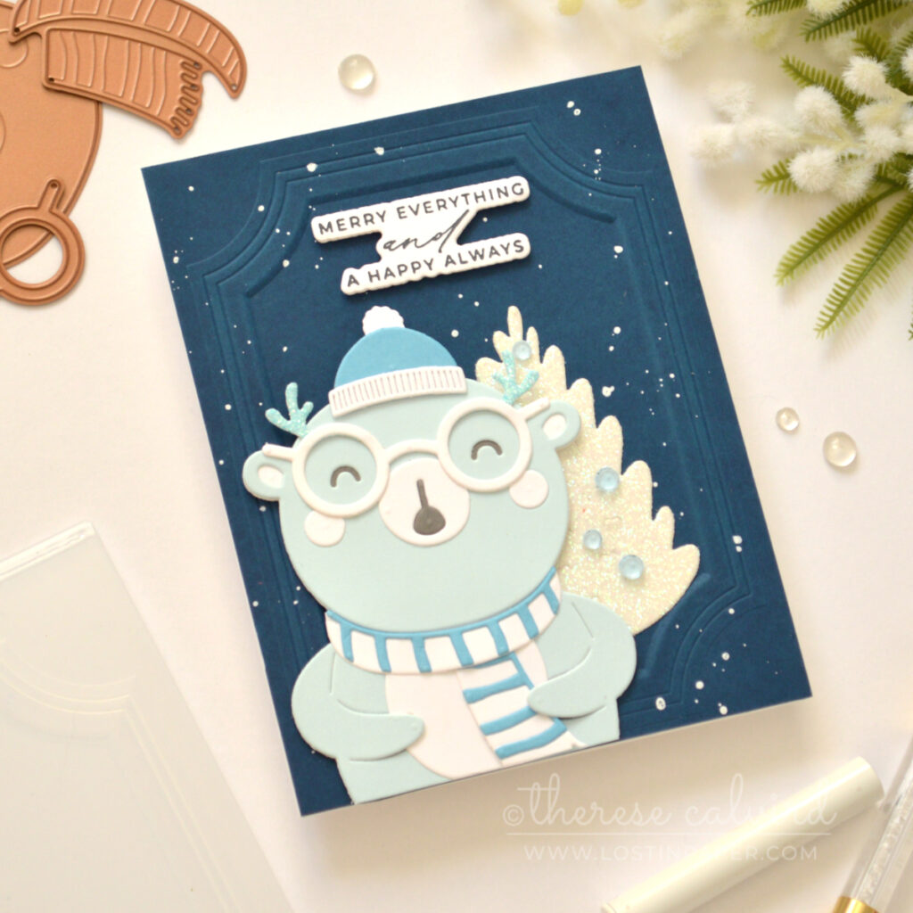 Blue bear Christmas card with a glittery white tree and dark blue embossed background.