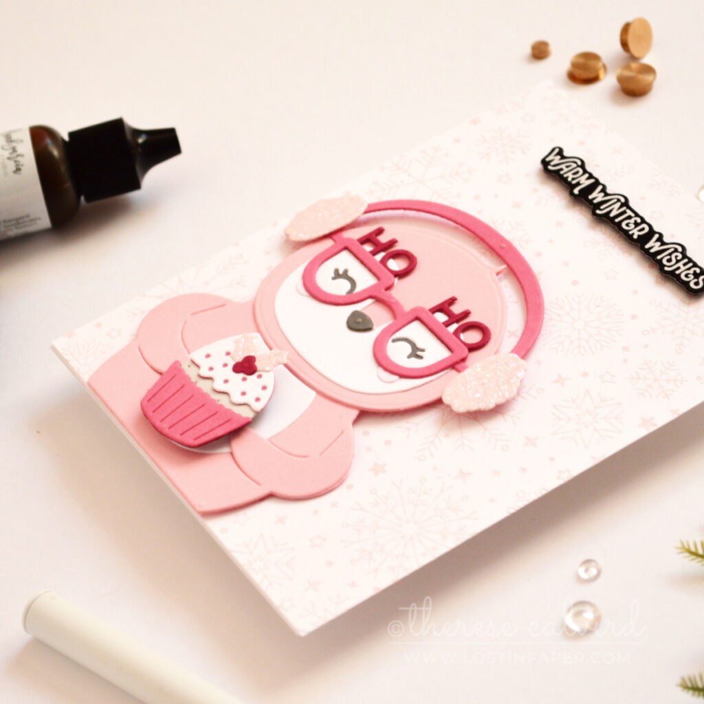 Pink penguin Christmas card with glitter earmuffs, spinning pudding and pale pink snowflakes.