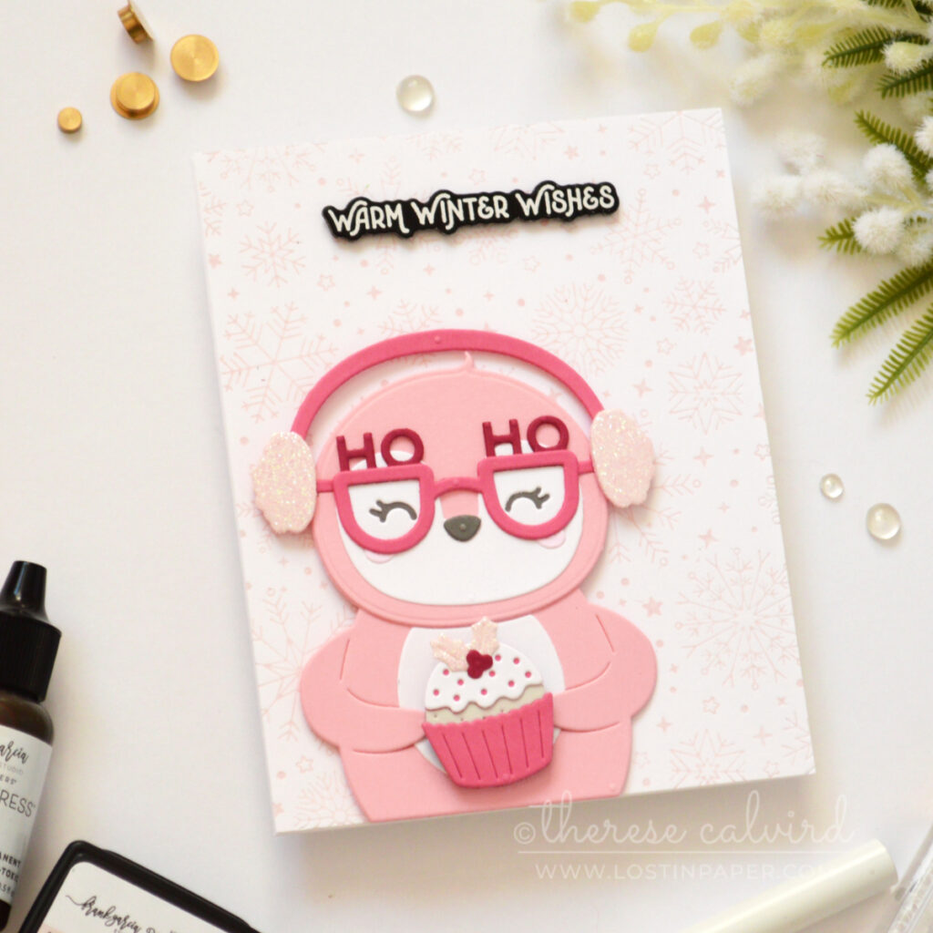 Pink penguin Christmas card with glitter earmuffs, spinning pudding and pale pink snowflakes.