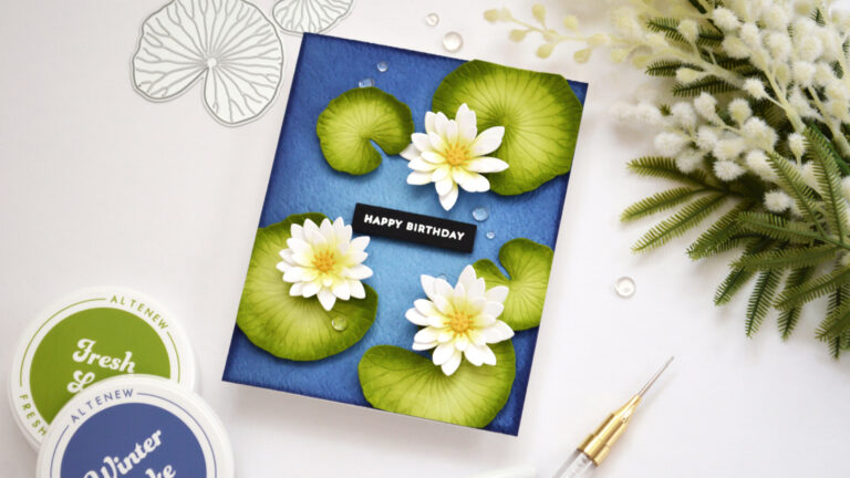 Handmade pond lilies birthday card with white and lime flowers, green lily pads, gold centres and water droplets on a textured blue background.