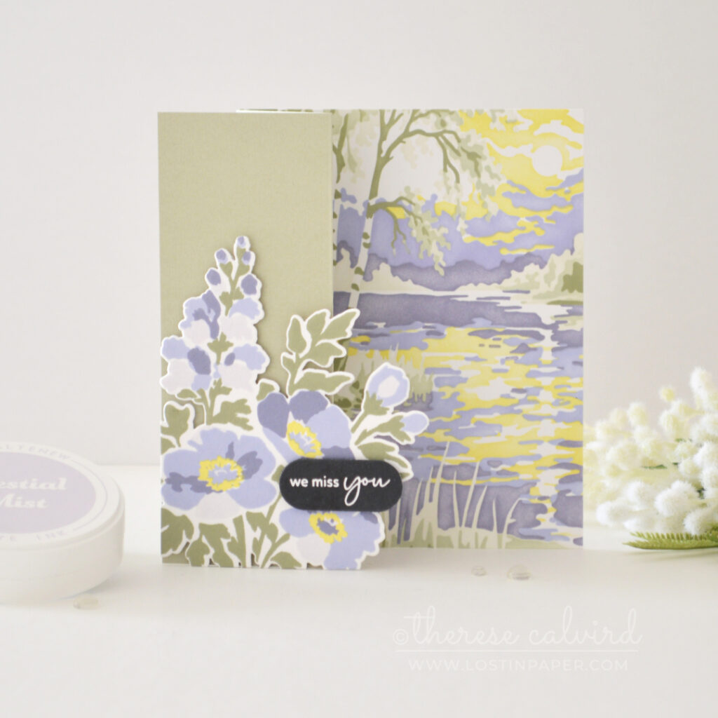 Sage green and purple floral Z-fold card with overhanging flowers, bold sentiment and a softly stenciled landscape background with yellow water reflection.