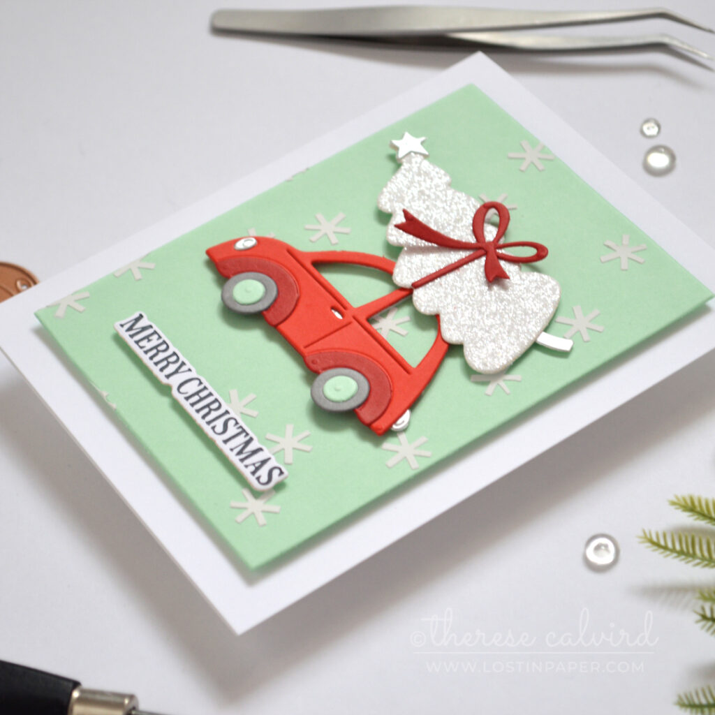 Mint Christmas card with white snowflake texture, bright red car and glittery white tree.