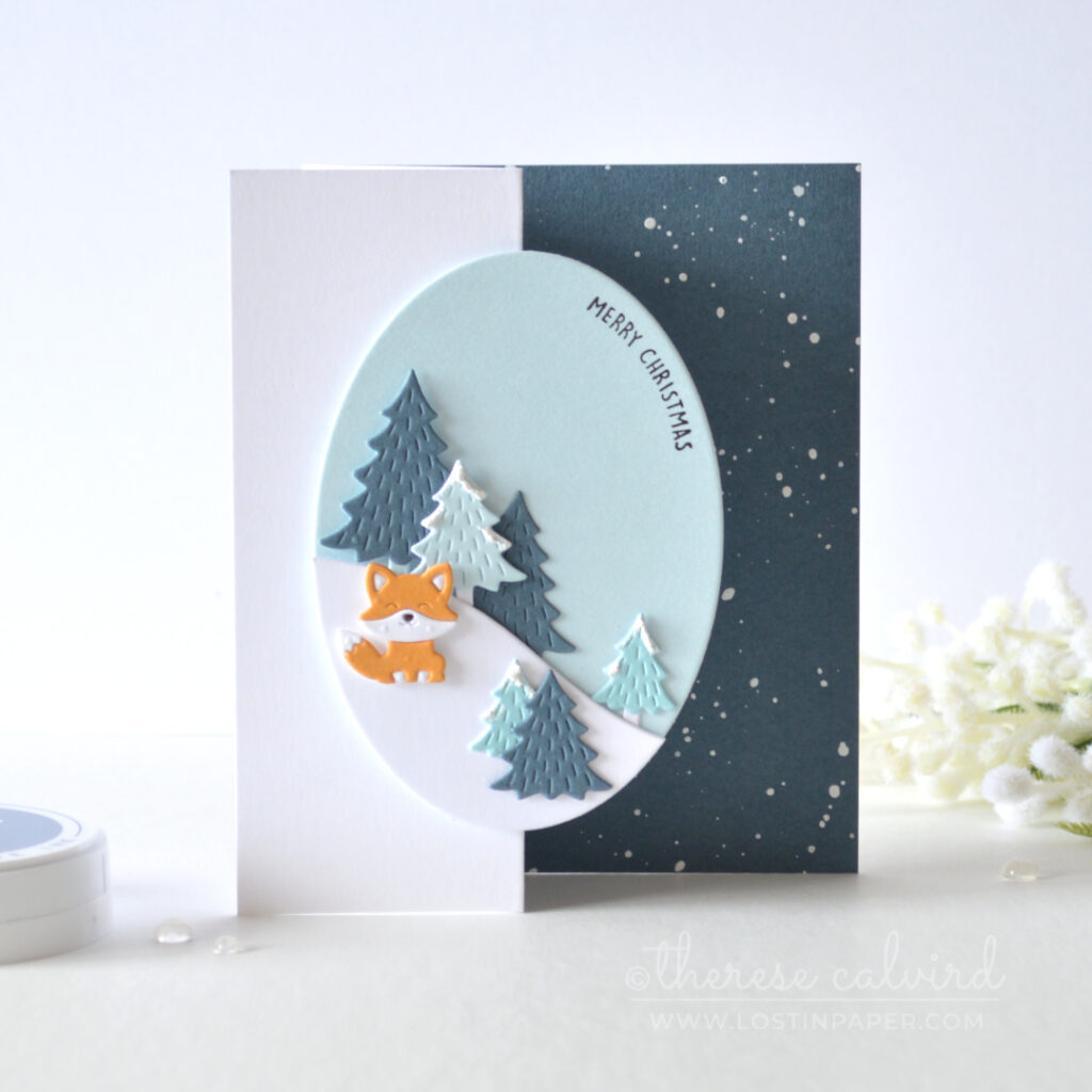 Blue Z-fold Christmas card with snowy trees, oval scene and orange fox by Therese Calvird