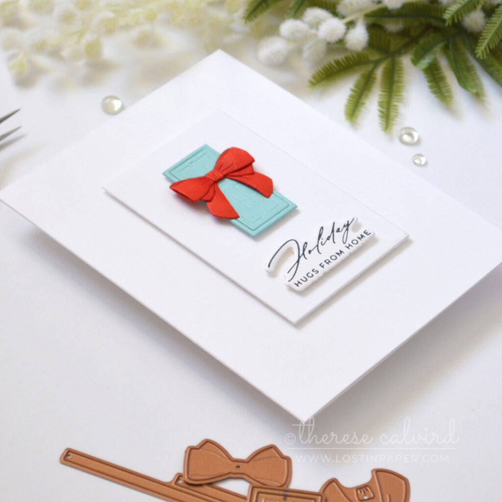 Clean and simple Christmas card with a blue door, dimensional red bow and sentiment on a white background.