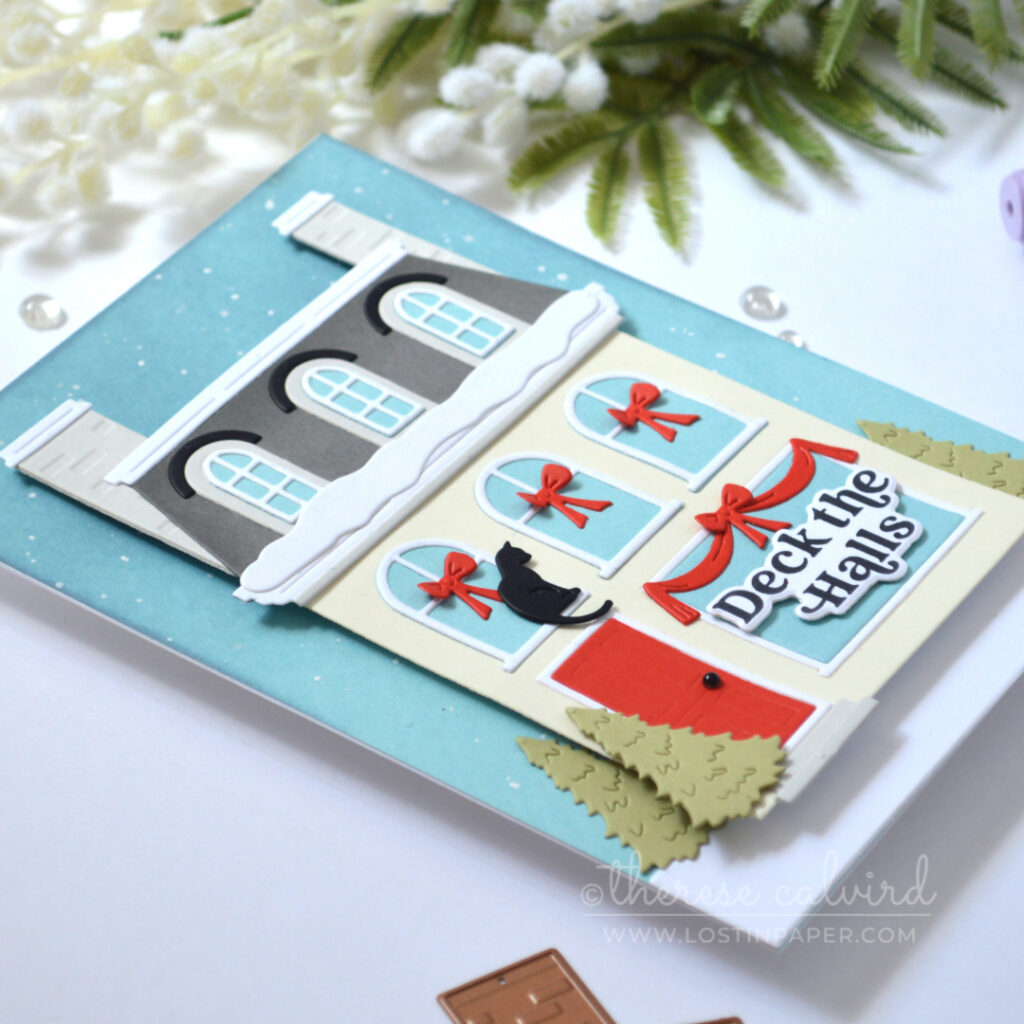 Cream City House Christmas card with grey Mansard roof, bright red door, snowy details, red window garlands and a black cat.