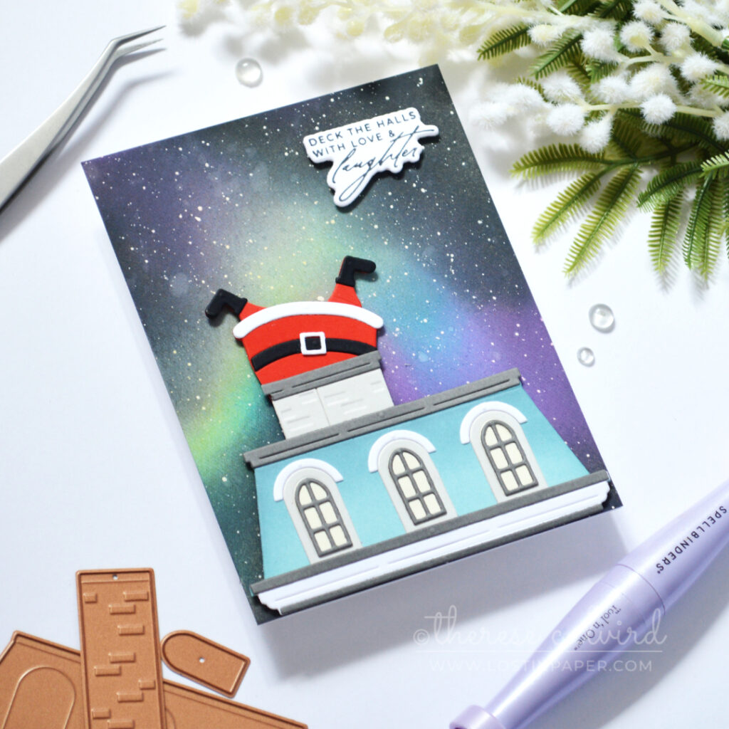 Christmas card with a blue Mansard roof, Northern Lights background and Santa stuck headfirst in a wide chimney.