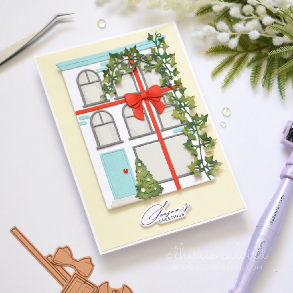 White City House Christmas card with blue roof and door, red bow, green vine, Christmas tree and vellum curtains.
