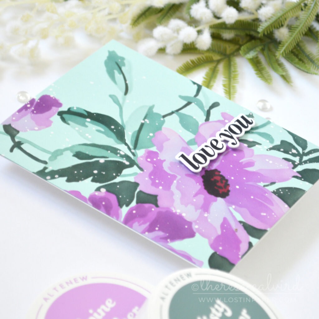 Handmade card with a large purple stenciled flower and teal foliage on pale teal cardstock, with a bold sentiment and white ink splatters.