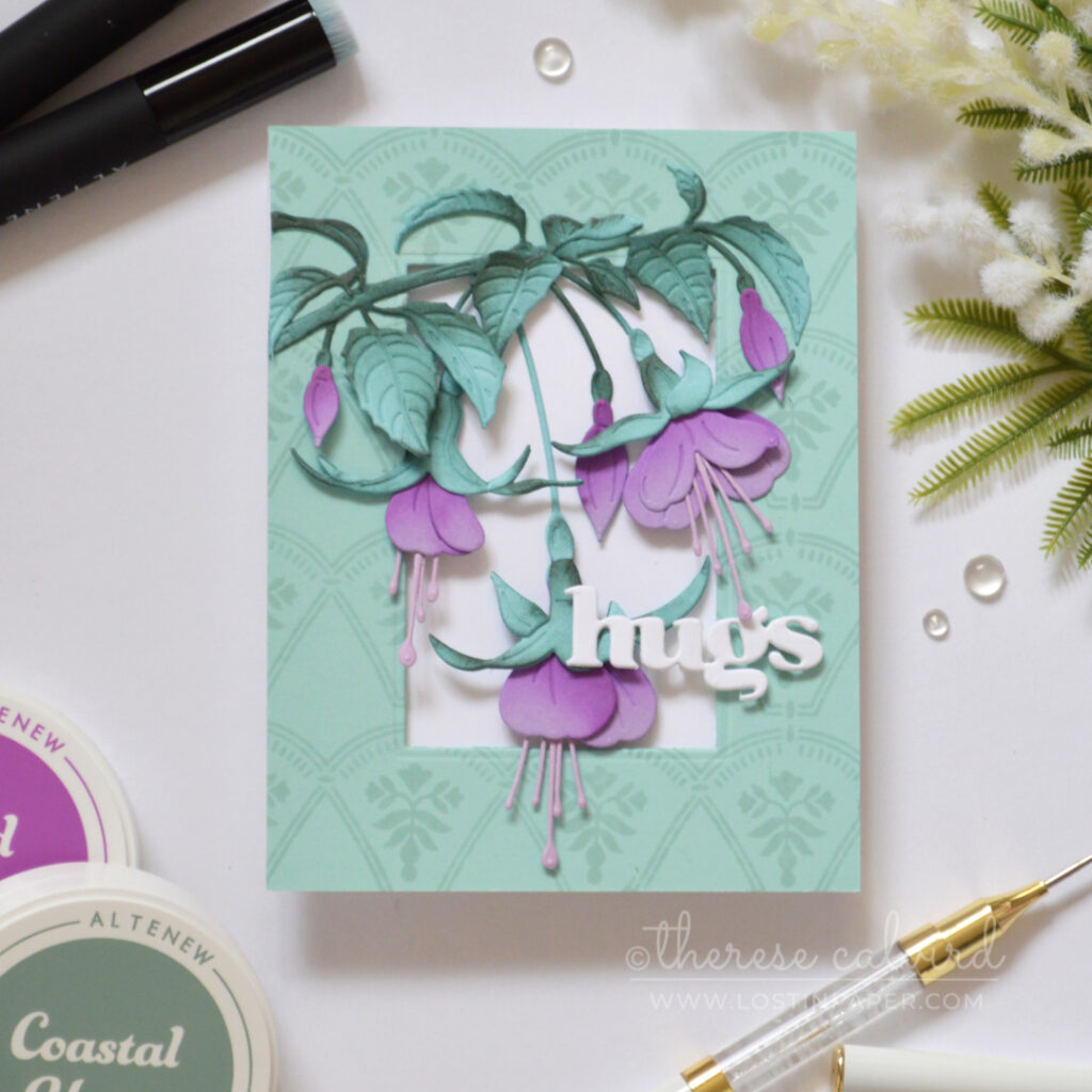 Handmade card with purple fuchsia flowers and teal leaves on a pale teal tone-on-tone stamped frame, finished with a white die-cut “hugs” sentiment.