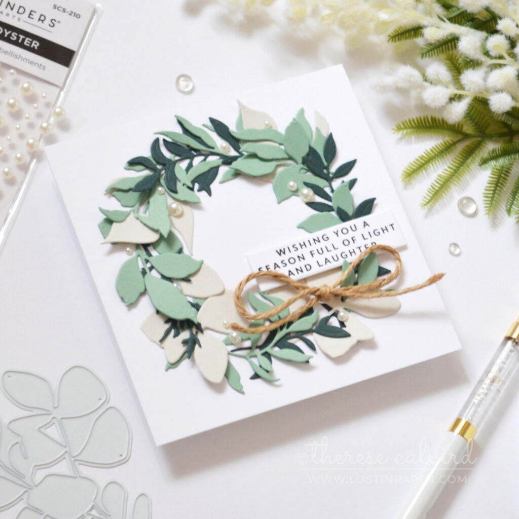 Christmas wreath card with layered eucalyptus-coloured leaves, pearls and twine bow.