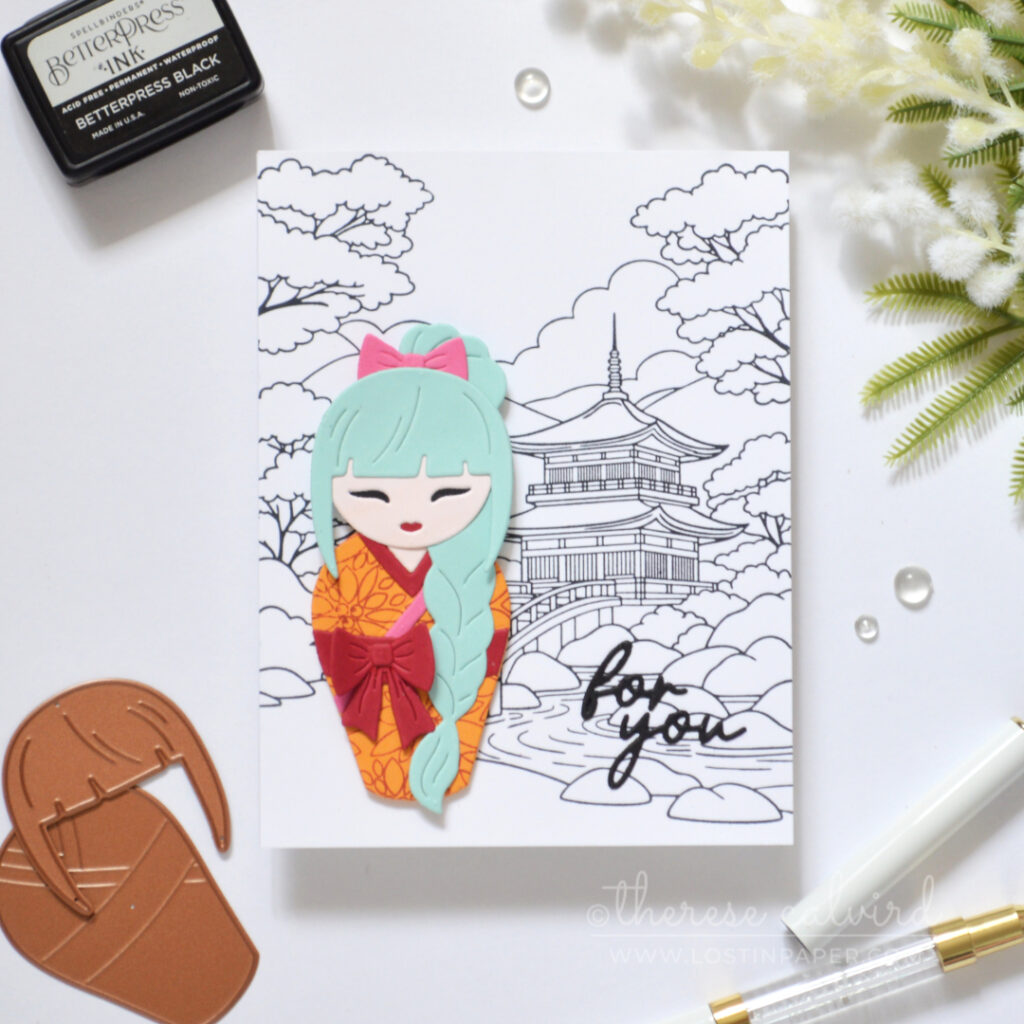 Die cut Kokeshi girl with teal plait on a black and white background.