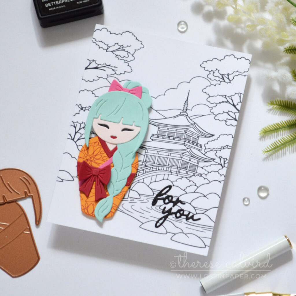 Die cut Kokeshi girl with teal plait on a black and white background.