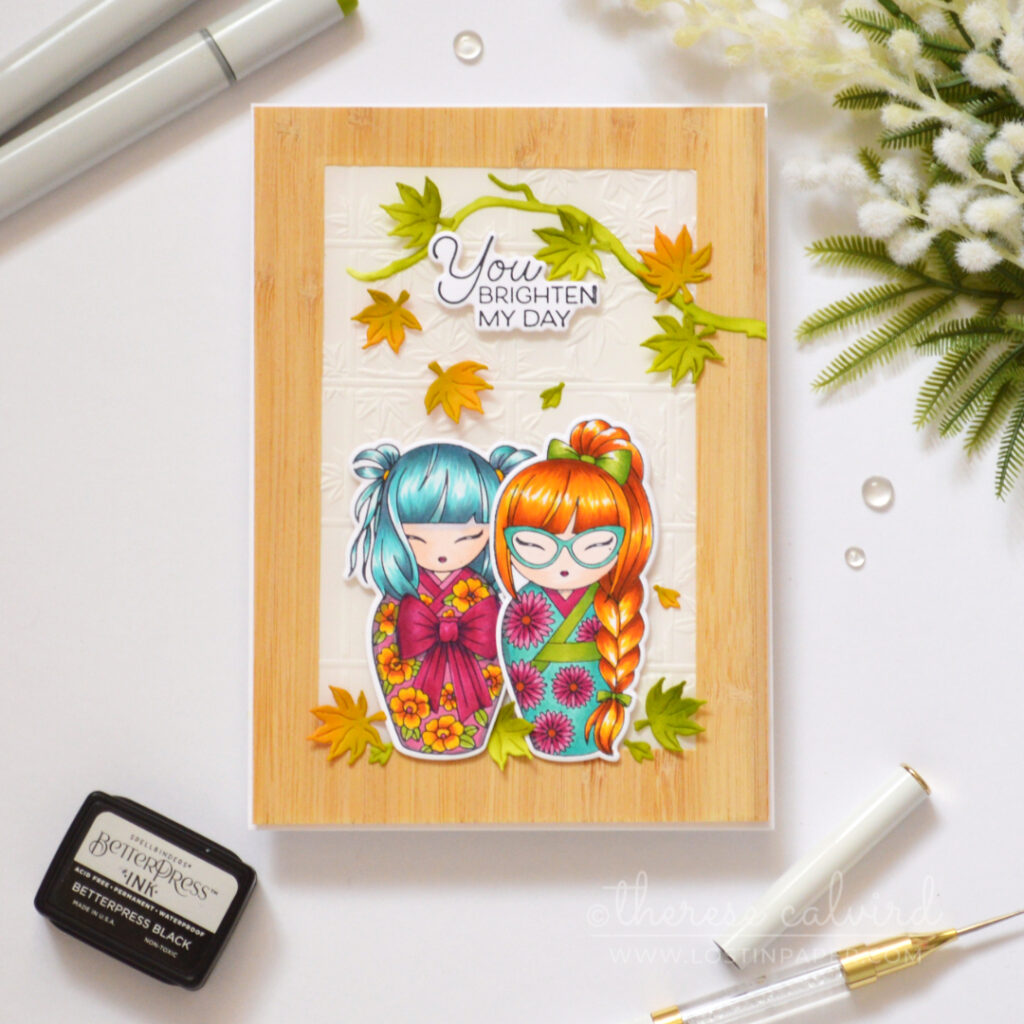 Two colourful Kokeshi girls framed by woodgrain and embossed vellum.