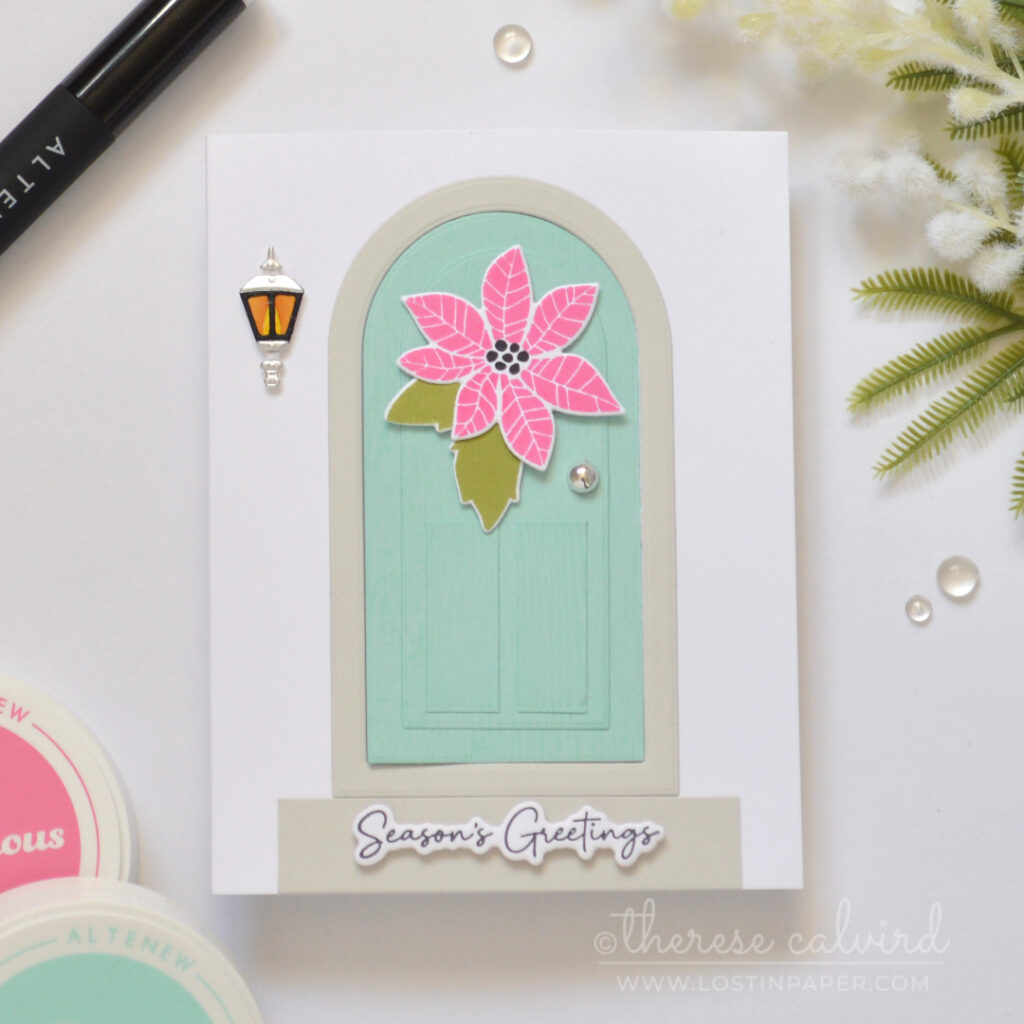 Interactive fun fold Christmas card with a light teal door, pink poinsettia, green leaves, lantern and silver door knob.